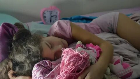 Adorable little girl night sleep in the sofa bed and hug indoors her baby d...