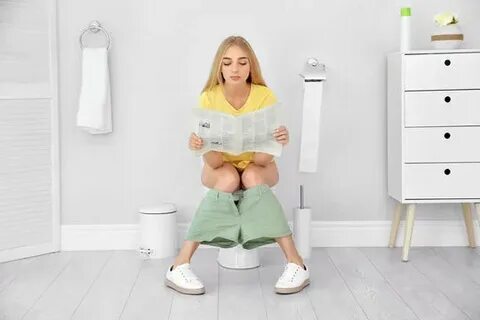Woman sitting on toilet reading