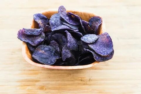 Heap of Purple Potato Chips on Wooden Background Stock Photo