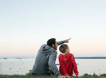 Father Sitting Together With Son Pointing Into The Sky by Ca