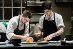 Chefs assemble a dish in a restaurant kitchen. - ABC News (A