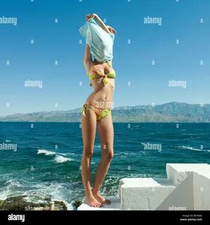Young woman wearing bikini, taking off shirt by sea Stock Ph