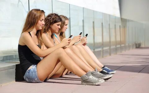 Drei Mädchen sitzen, um Telefone zu benutzen 1080x1920 iPhon