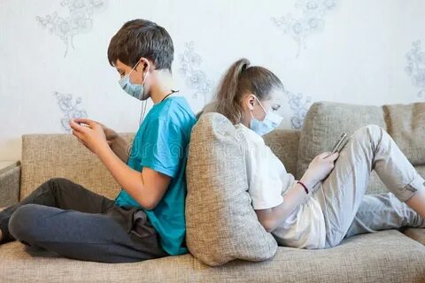 Брат и сестра, используя свои смартфоны, сидя на диване дома
