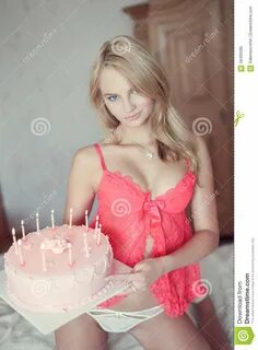 blonde woman with birthday cake kneeling on bed.