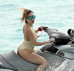 lauryn goodman in a golden swimsuit riding a jet ski in barb