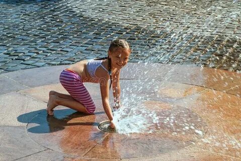 Girl on a Sunny Warm Day Playing Outside in a Water Fountain
