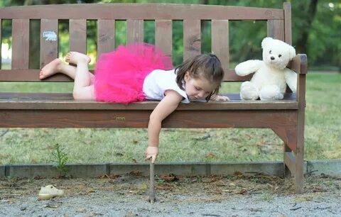 little girl lying on a bench in the park. 