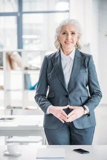 Smiling senior businesswoman standing in office and looking 
