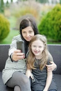 Mother and daughter sitting in nature and talking selfie. Wi