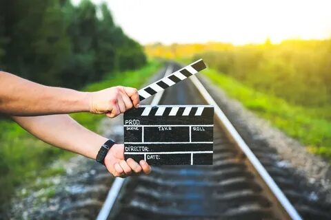 Guy is holding black clapperboard in hands. Man is directing