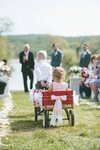 Ring bearer pulling the flower girl down the aisle in a red 