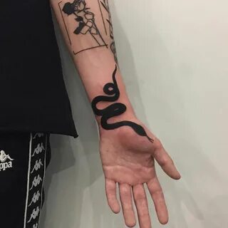 Black snake tattoo on the left arm’s inner wrist. Hand tatto