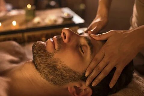 Close-up of a man relaxing with eyes closed during head massage at the spa....