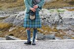 Person in beautiful and colorful kilt, holding bagpipes on I