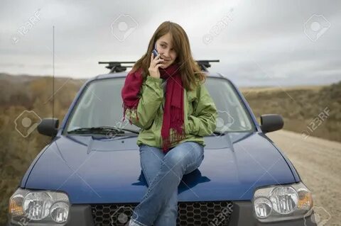 Teen Girl Sitting On The Hood Of A Car, Calling Or Texting O