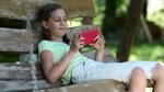 girl red smartphone sits on swing: стоковое видео (без лицен