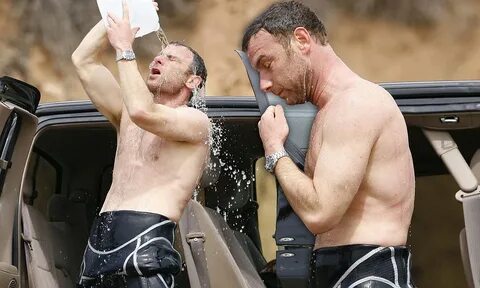 Muscular Liev Schreiber peels down his wetsuit and douses hi
