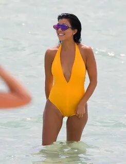 Kourtney Kardashian wearing low-cut yellow swimsuit at the b