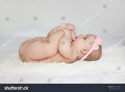 Стоковая фотография 467743997: Naked Baby Girl Chewing On He