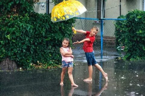 Cheerful Boy and Girl with Umbrella during Summer Rain Stock