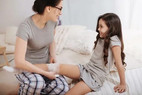 Delighted Mother Bandaging Daughter Leg Home Photos - Free &