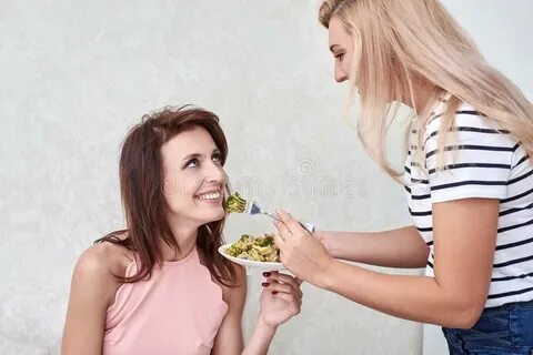 Two Women Feeding Each Other in the Kitchen Stock Image - Im