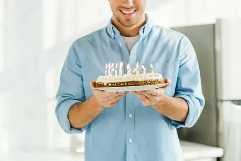 Cropped view of smiling man holding birthday cake with burni