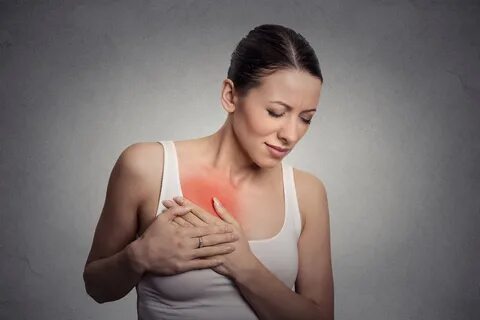 young woman with breast pain touching chest.