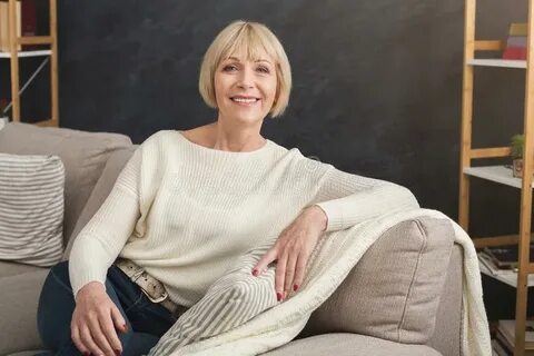 Portrait of Beautiful Middle Aged Woman Sitting on Sofa Stoc