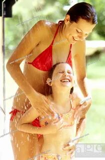 Mother and daughter in bathing suits in outdoor shower, Stoc