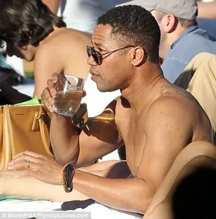 Cuba Gooding Jr. relishes a glass of white wine by the pool 