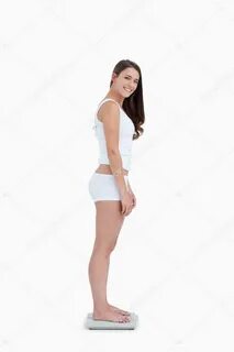 Smiling woman standing on weighing scales while looking at t