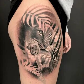 Black and grey lioness and cub tattoo on the thigh.