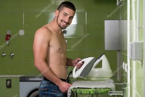 Nackter Mann bügelt Kleidung im Hauswirtschaftsraum - Stockf