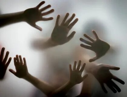 Many hands in silhouette pressed against frosted glass Hand 