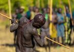 Suri tribe warrior bleeding during a donga stick fighting . 