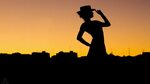 Silhouette of woman holding hat while standing HD wallpaper 
