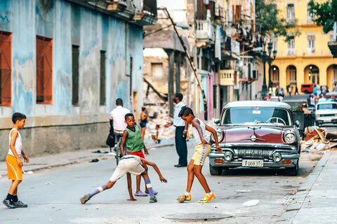 Cuban boys playing soccer on a dusty street in Havana. The H