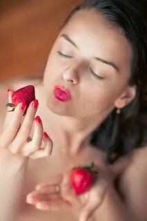 Photo of seductive female eating strawberry, closeup portrait of redhead se