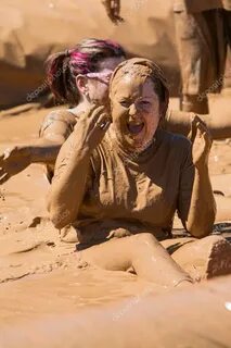 Мутная женщина сидит и смеется над девушкой, бегущей по гряз