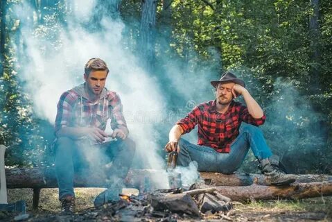 Two Young Guy Sitting in the Forest and Drinking Beer Near C