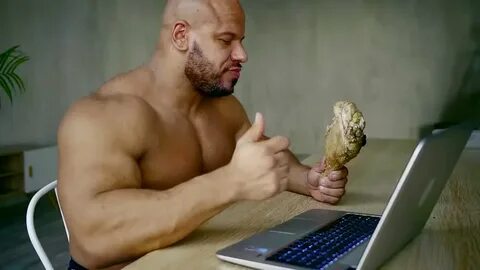 Naked hungry man is eating fried leg, holding it. - Royalty 
