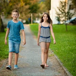 Young teenage boy and girl walk in park in the city - Licens