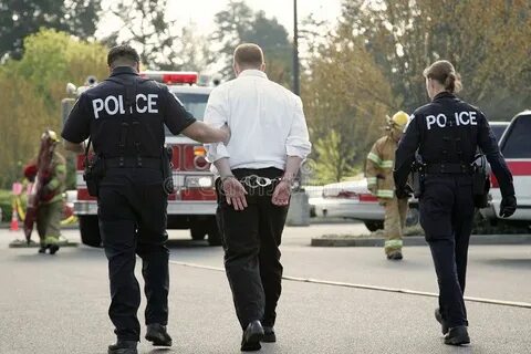 Under Arrest. Police officers arresting young man in handcuf