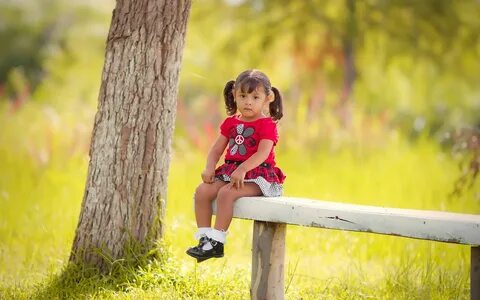 Маленькая девочка на скамейке в солнечном лесу Обои на рабоч