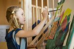 Preschool girl painting A preschool student paints at an e. 