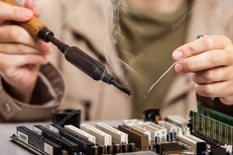 Human hand holding soldering iron repairing computer circuit