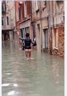 Acqua alta a Venezia, una donna cammina senza vestiti per la