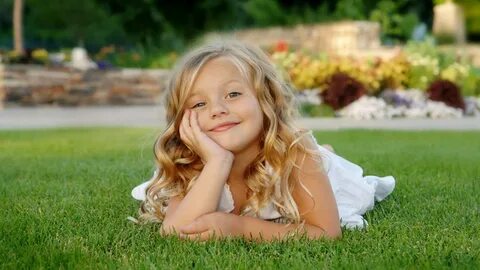 Smiley Cute Little Girl Is Lying Down On Green Grass Wearing